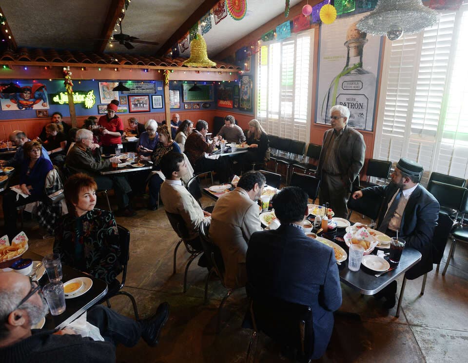 Nidal Alsayyed seated with others at a community meal