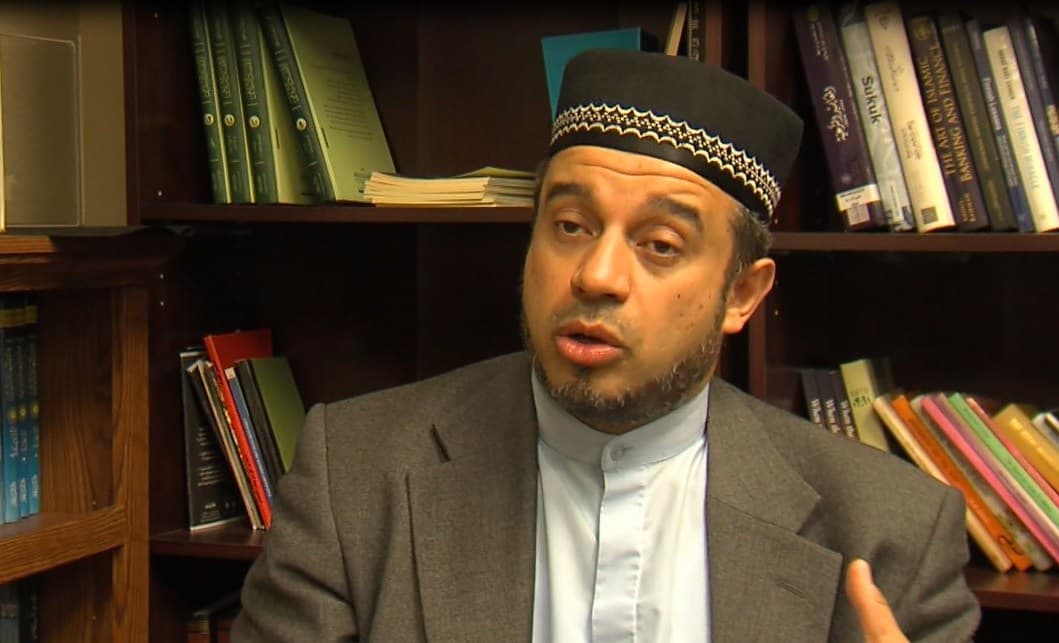 Nidal Alsayyed speaking in front of a bookshelf