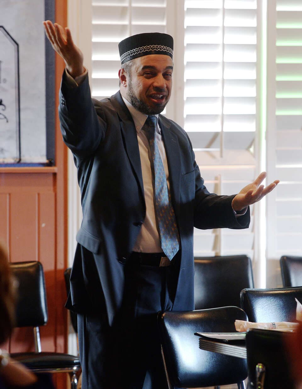 Nidal Alsayyed with arms open while addressing an audience